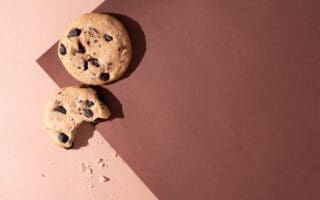 Two chocolate chip cookies on brown paper background in sunlight