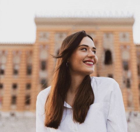 a woman smiling in front of a building