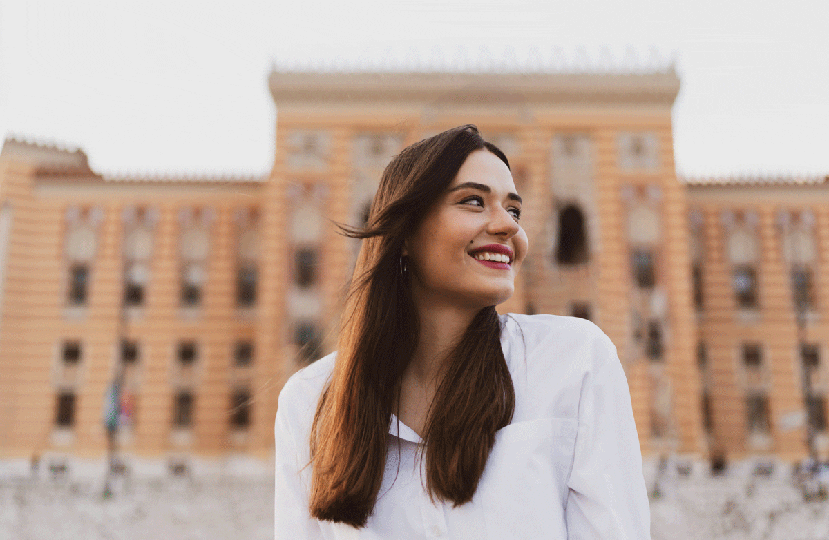 a woman smiling in front of a building