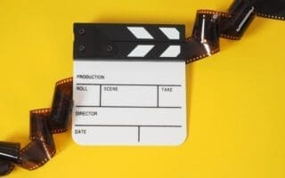 Small white clapper board and film roll on yellow background