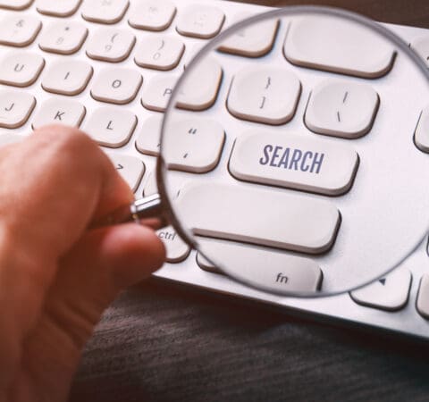 Word search on keyboard key seen through mangifying glass